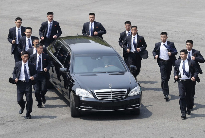 中午時分，北韓領導人金正恩搭乘專車暫時返回北韓用餐，12名保鑣圍著車輛向前跑。AP