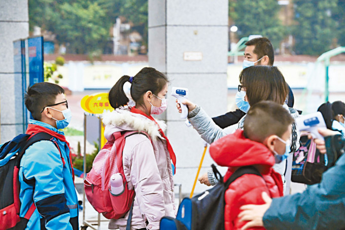 重慶一小學學生戴口罩，測溫進入校園。