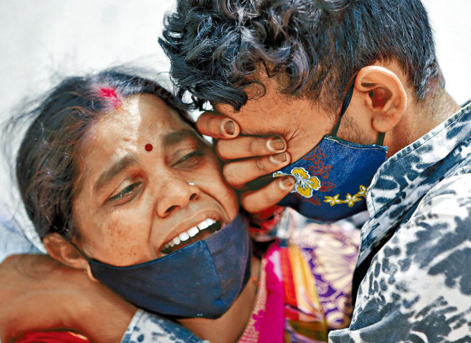 印度婦女的丈夫死於新冠肺炎，與兒子哀痛相擁。