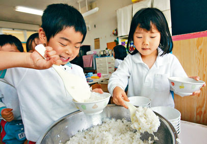 日本滋贺县守山市的学童午餐时盛饭。　