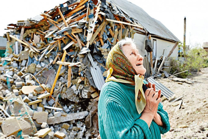 烏東頓涅茨克萊曼市一婦人站在遭導彈摧毀的房屋旁，仰天哭泣。