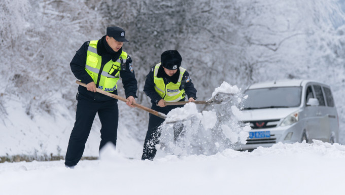 警察抢通被暴雪封堵的的公路。