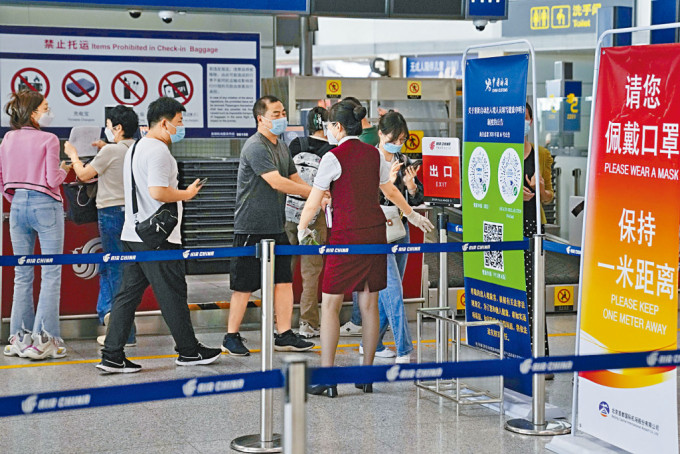北京機場工作人員昨天引導旅客辦理登機手續。