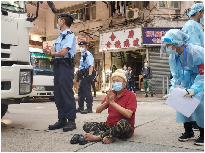 男子在炮台街近寧波街，坐在馬路上替區內受疫情影響的居民祈福。