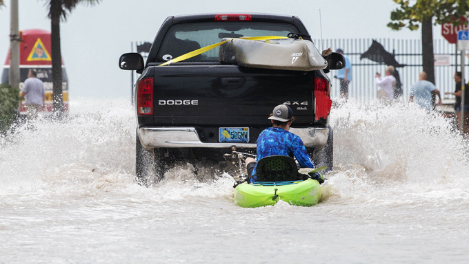 佛州基韦斯特市在伊恩飓风吹袭期间洪水泛滥，一辆客货车在水浸的道路上拉著一名男子乘坐橡皮艇。AP