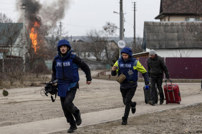基輔附近的伊爾平市遭猛烈砲擊後，當地記者尋找掩護。REUTERS