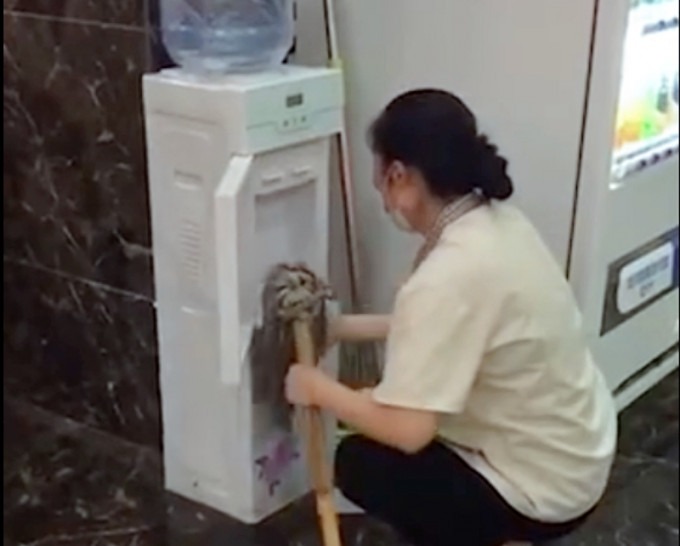 清洁女工用地拖擦拭饮水机。网图