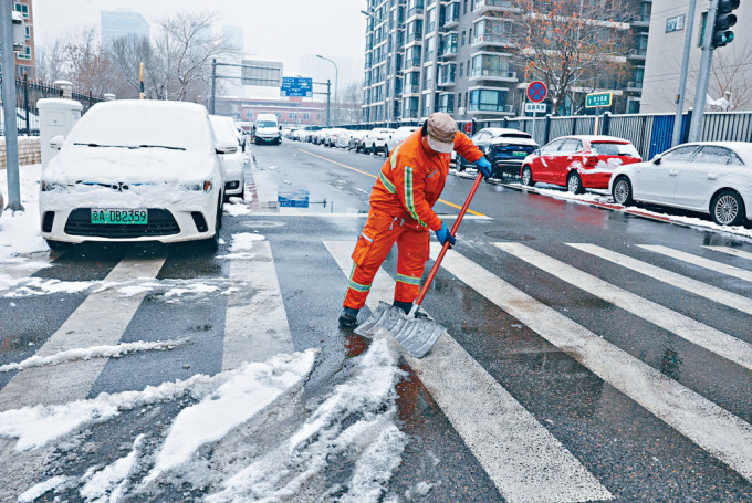 北京街头正在铲雪的环衞工人。