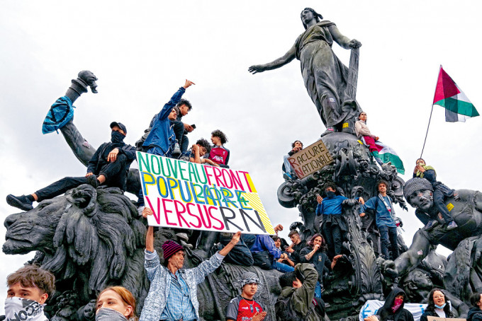 示威者在巴黎攀上雕像展示反極右標語。
