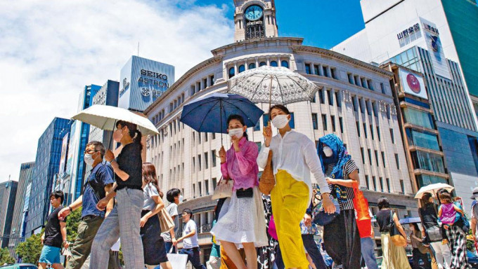 东京天气炎热，途经银座区的民众纷纷撑伞遮太阳。