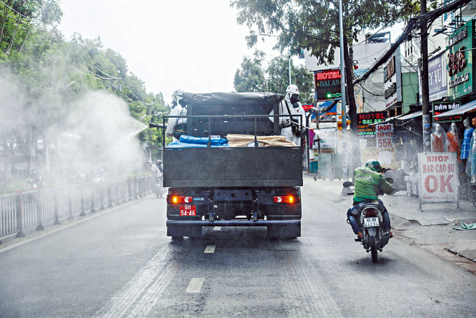 ■在疫情升溫的胡志明市，當局派專車在街上噴消毒劑。
