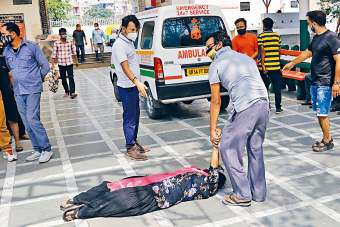 ■新德里一名女子在火葬场，见到死于新冠肺炎的亲人遗体后晕倒。