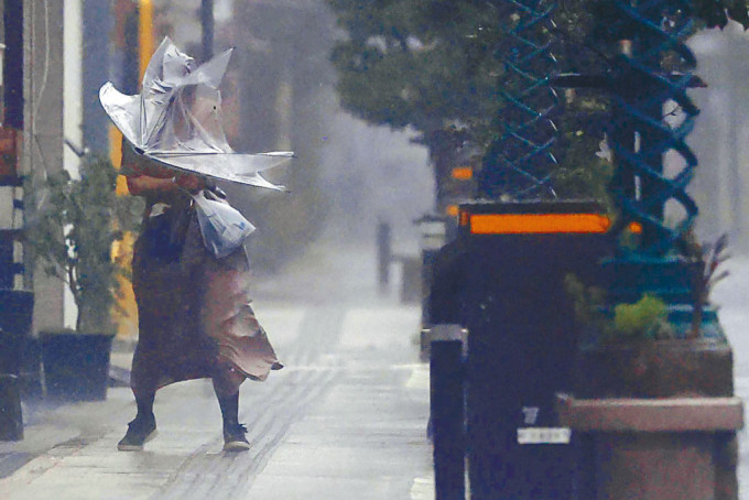日本南部宮崎縣一名女子周日在颱風「南瑪都」吹襲下，舉傘冒着風雨前行。