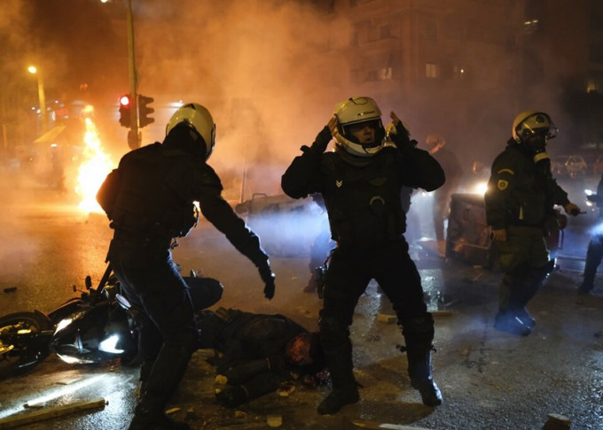 希臘爆發警民衝突，有警員在衝突現場幫助倒到受傷的同袍。AP圖