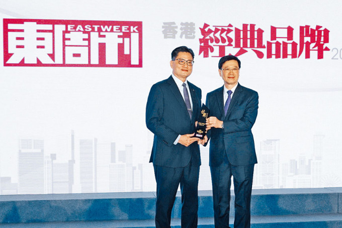 特首李家超（右）颁发「百年经典品牌」大奖予「香港中华煤气」，由中华煤气企业事务总监杨松坤（左）代表领奖。