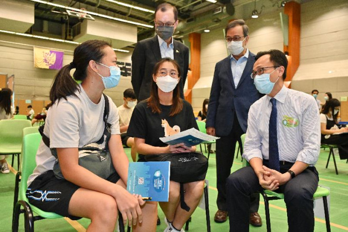 聂德权（前排右）与准备接种新冠疫苗的学生交谈。政府图片