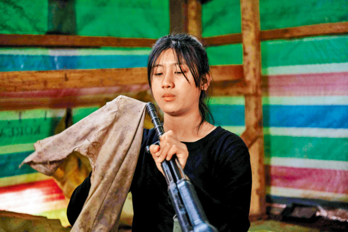 人民防衛軍（叛軍）一名女兵在緬北撣邦營地擦拭武器。
