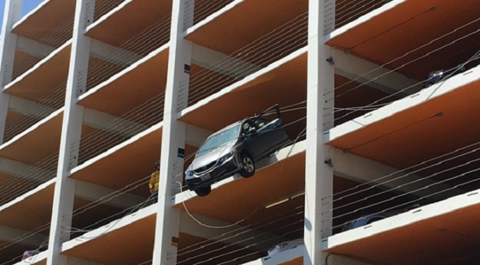 美国一名六旬妇在停车场驾驶期间，错将油门当成煞车，结果私家车加速，并冲出安全围栏，悬吊在4楼半空。