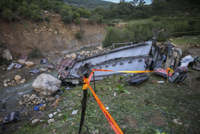 巴士墜崖，車頭全毀、遺體散布河床。AP
