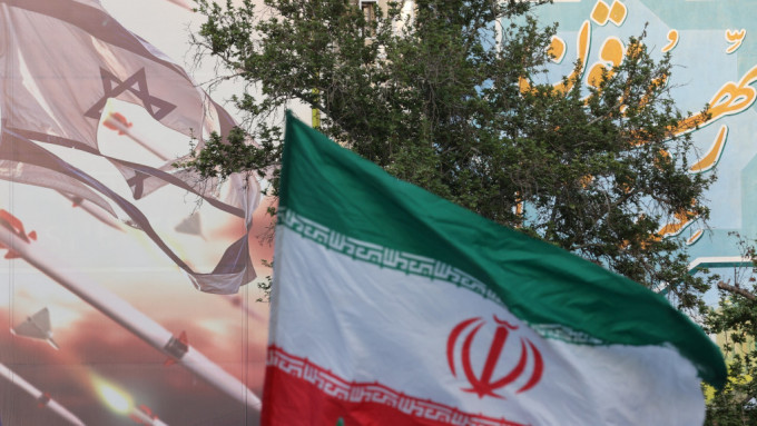 伊斯兰革命卫队攻击以色列后，人们上街庆祝，在巨型反以壁画旁挥舞伊朗国旗。路透社