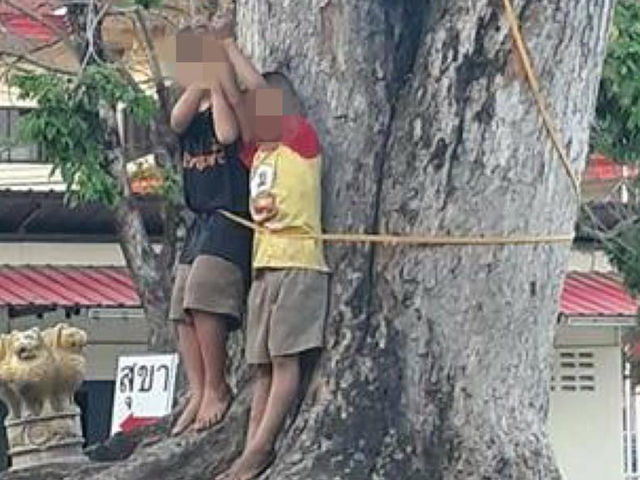 两名男童被绑在大树上打骂。 网图