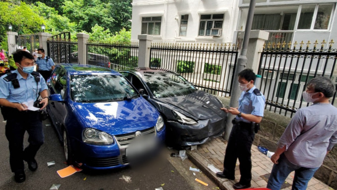 Tesla撞到泊路邊藍色私家車，又鏟上行人路撞低女途人，警員到場調查。楊偉亨攝