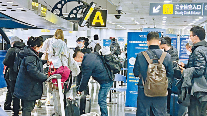 中國打開國門，首都國際機場旅客在國際及港澳台出發大廳排隊安檢。