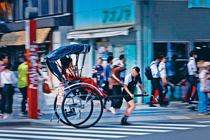 女人力車夫在東京淺草街頭，拉着客人觀光。