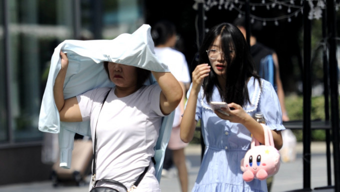 在西安市民撐起衣服遮擋猛烈的陽光。中新社