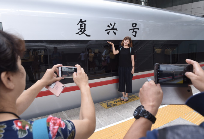 乘客在天津站月台上和「復興號」合影。新華社