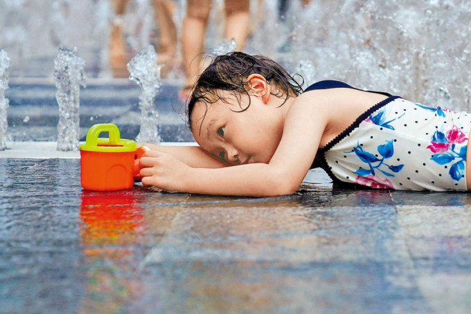 一名女孩在喷水池降温。