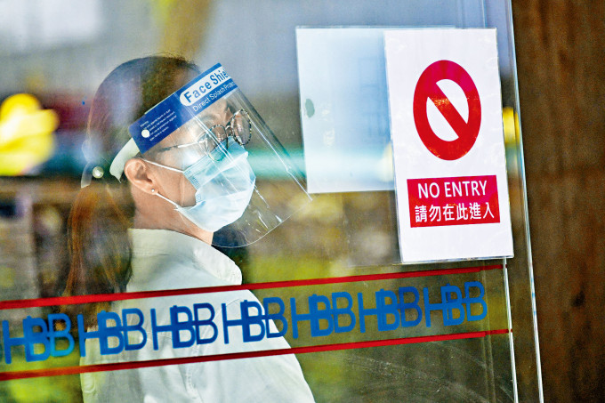 肺炎疫情確診個案屢創新高，上環海港政府大樓正門保安員，佩戴口罩面罩自保。