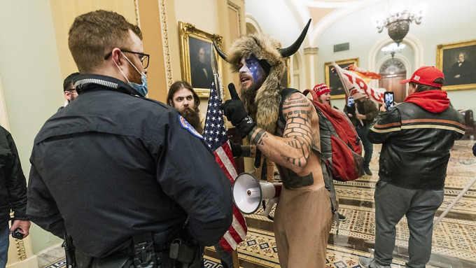 在華盛頓進入國會大樓的一班美國市民當中，有一位更戴着動物角和披着獸皮，這個標誌性人物便是QAnon的一分子。AP