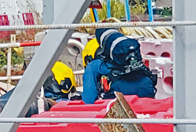 ■消防员背上氧气樽在现场工地调查及探测污水井内气体情况。