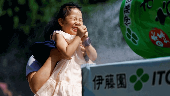 日本一個女童在噴霧器前降溫。（路透社）