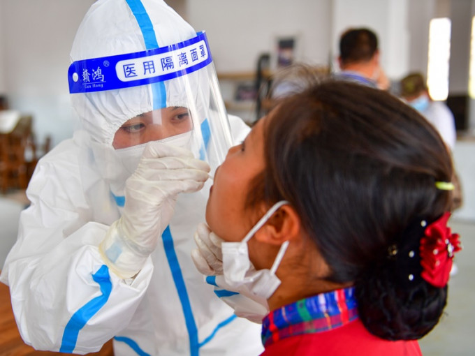 瑞麗市一核酸檢測點醫護人員為市民進行核酸取樣。新華社
