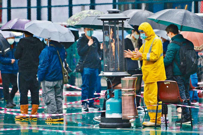天氣持續寒冷，不少市民捧傘冒寒排隊檢測。
