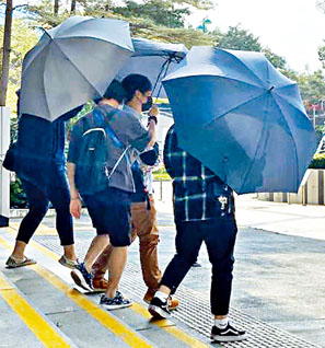 ■被告廖子浩（啡色褲）被罰款一千元，被親友以雨傘遮掩接走。
