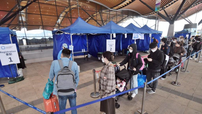 旅客在旅檢大樓外排隊，等候接受額外的免費核酸檢測。