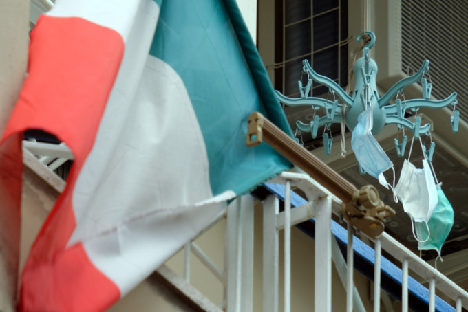 意大利米兰市有居民在露台悬挂国旗以名口罩。AP图