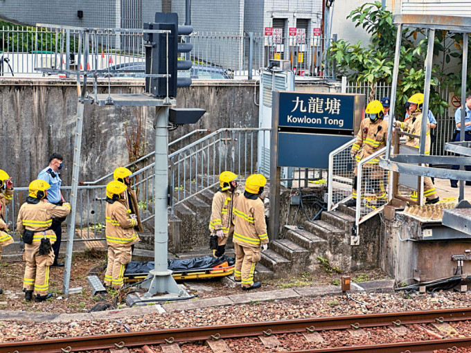 消防员将疑躺卧路轨遭列车辗压的男子尸体舁送往月台上。