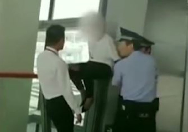 迟到被拒登机女乘客爬上栏杆与警员「对峙」。（网图）
