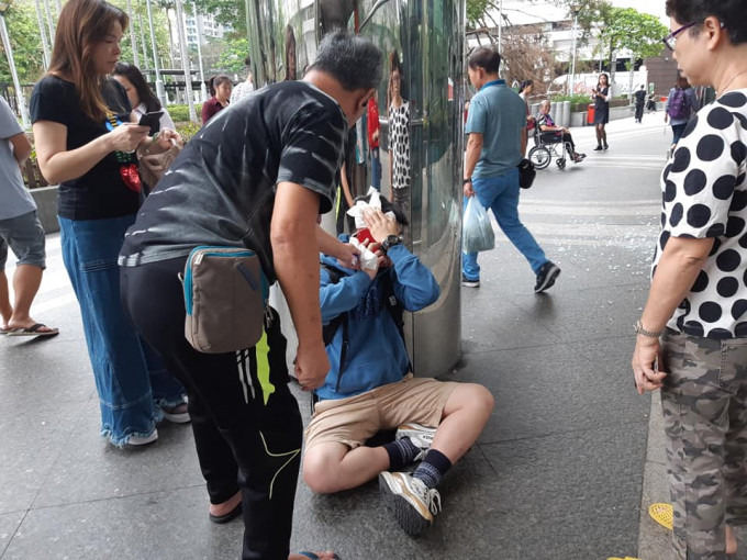 男伤者坐在地上，途人上前帮忙。  香港突发事故报料区FB/网民The Nini C‎图