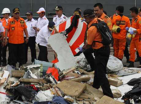 工作人員在雅加達的一個碼頭貨倉檢查飛機殘骸和尋獲的乘客私人物品。AP