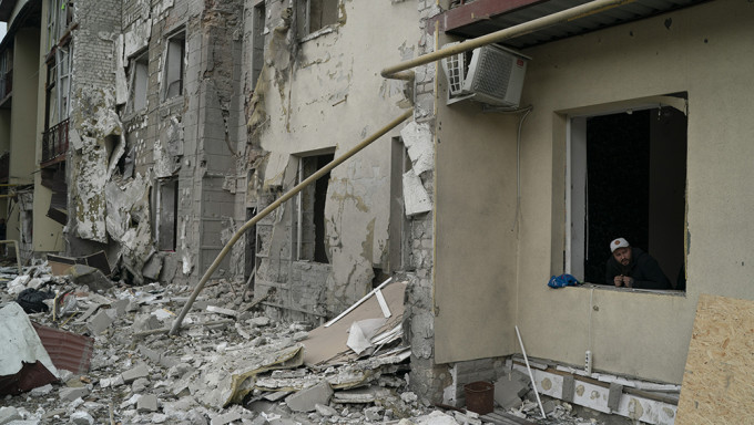 俄军在哈尔科夫发动袭击后，一名男子从一栋住宅楼的窗户向外望去。AP