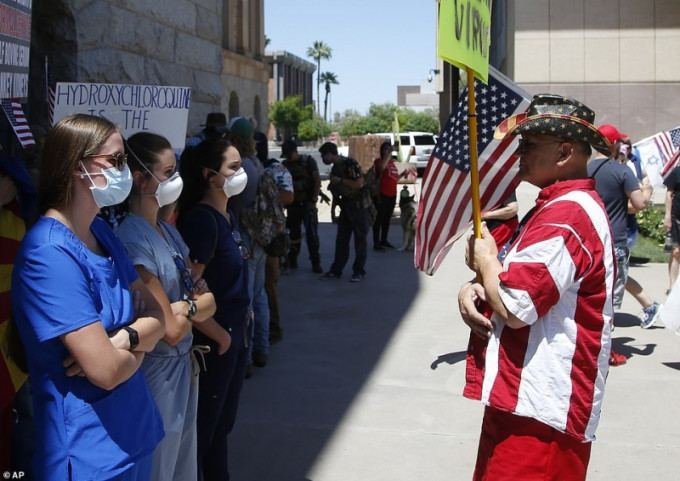 医护人员与要求取消居家令的示威者对峙。AP图