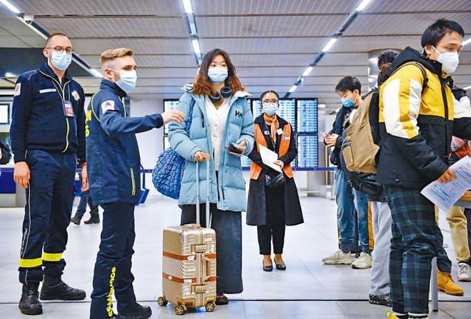 上月初，法國機場人員檢查中國旅客的核酸證明。