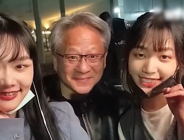黄仁勋（中）和两位台湾女网红歌手在镜头前唱歌。