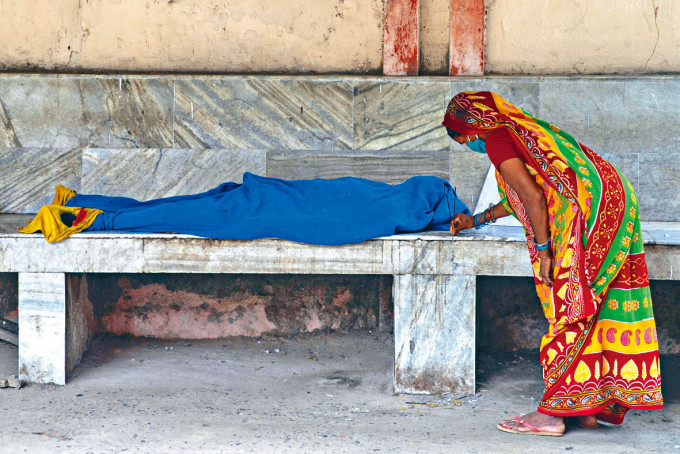 印度比哈尔邦医院新冠死者遗体等候运走，女亲属在旁点香。