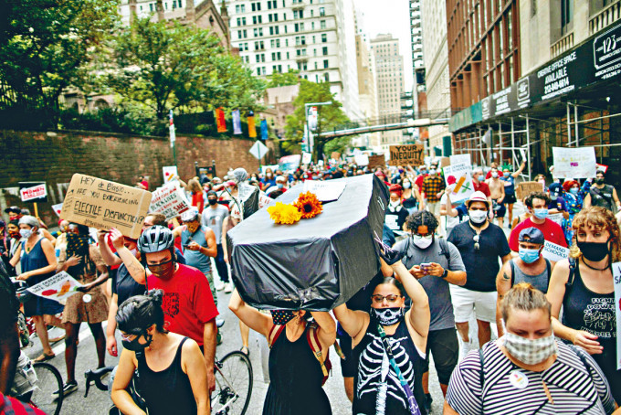 纽约反对学校重开示威者抬着假棺材游行，象徵染疫死亡学生。